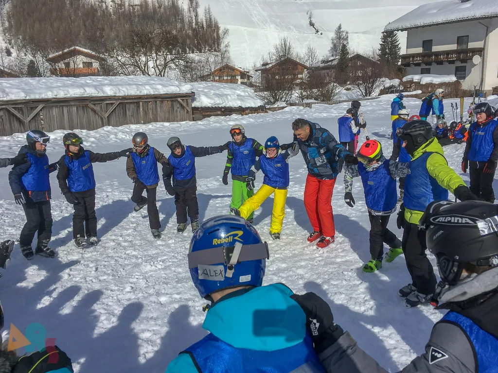 Skigruppe steht im Kreis auf der Übungswiese.